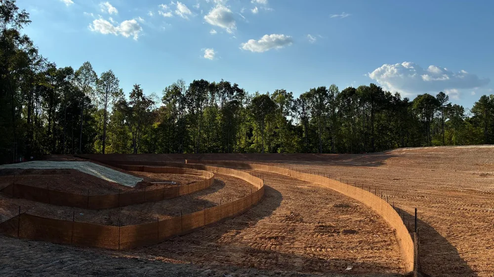 Curved erosion control matting and silt fence installed across a graded North Carolina site